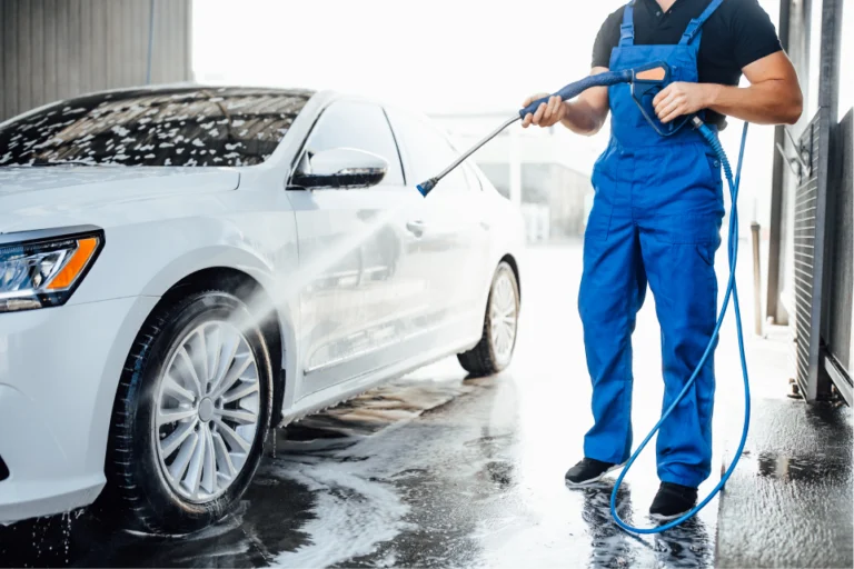 professional_washer_blue_uniform_washing_luxury_car_with_water_gun_open_air_car_wash